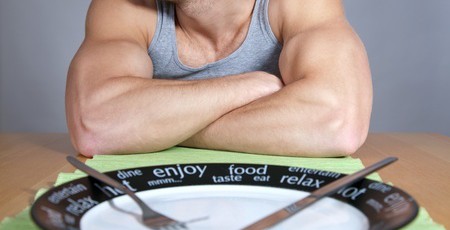 13275526 - muscular man sitting at the table with empty plate
